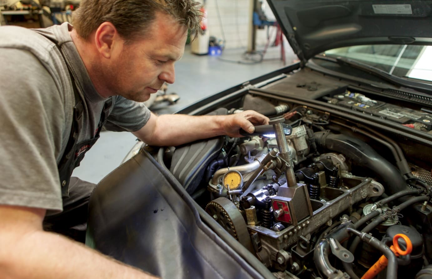 Monteur meet met een meetklok aan een geopende dieselmotor in de werkplaats