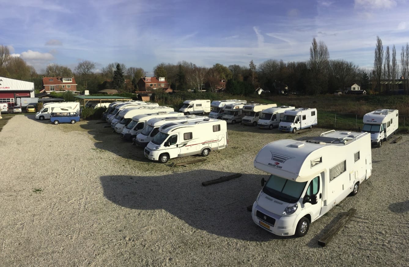Rij campers op het stallingsterrein achter de garage onder een blauwe lucht