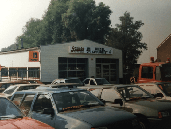 Gevel met het bord Jacobs Diesel Specialist en auto's ervoor